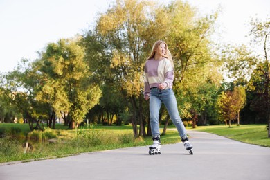 Photo of Happy young woman roller skating in park
