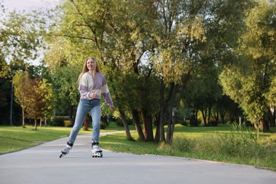 Photo of Happy young woman roller skating in park