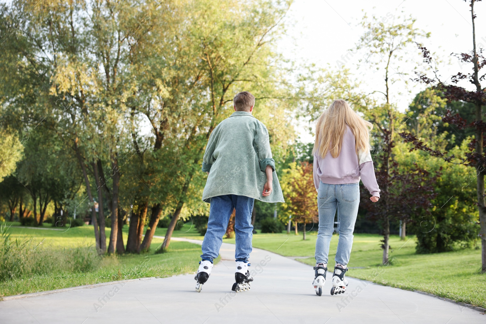 Couple roller skating together in park on summer day Photo of Couple roller skating together in park on summer day