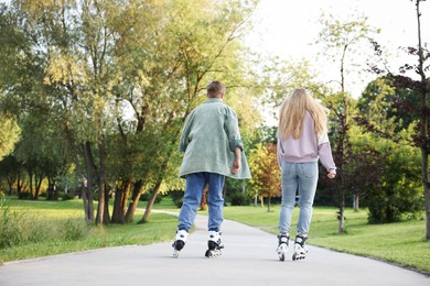 Photo of Couple roller skating together in park on summer day