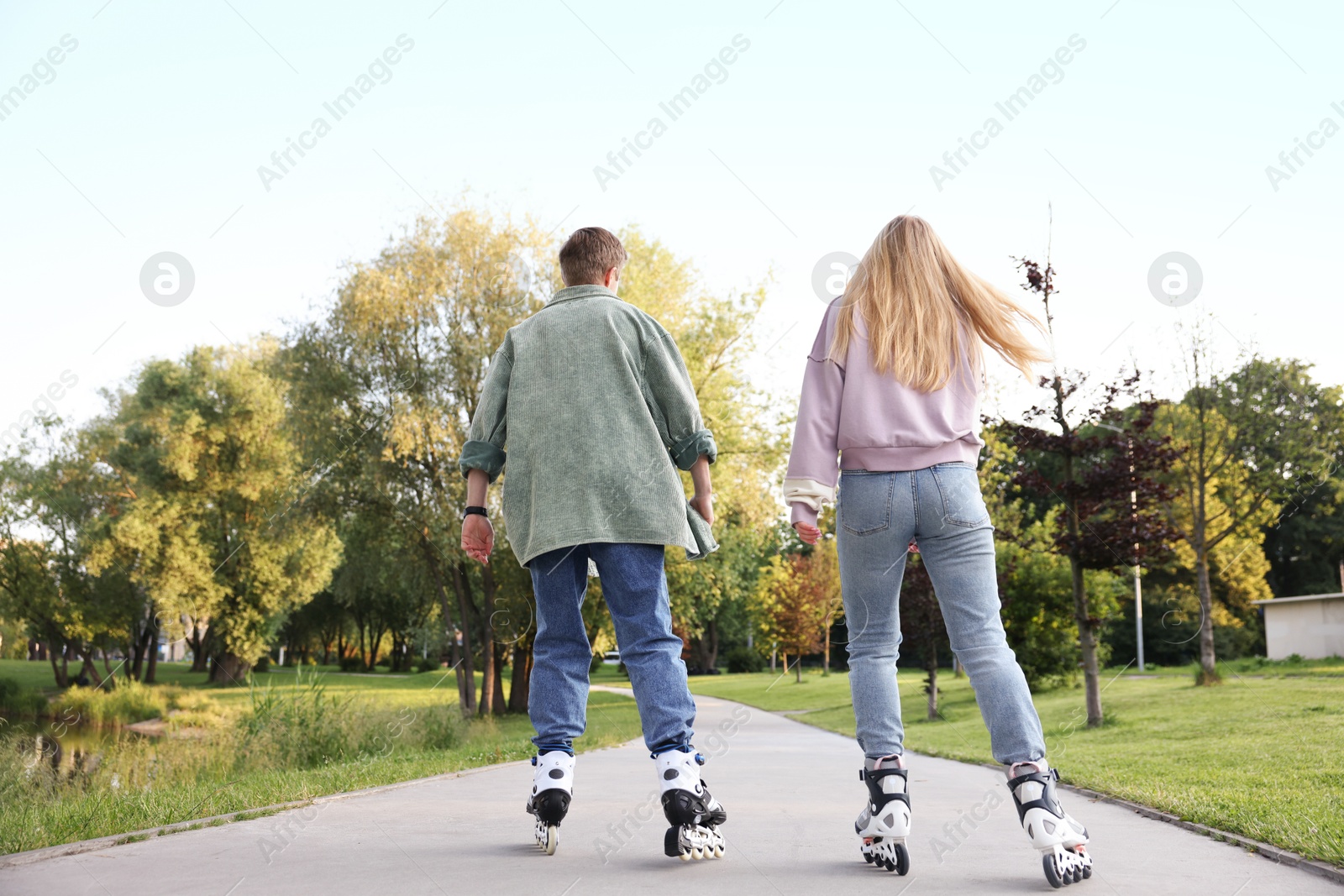 Couple roller skating together in park on summer day Photo of Couple roller skating together in park on summer day