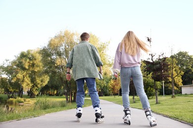 Photo of Couple roller skating together in park on summer day