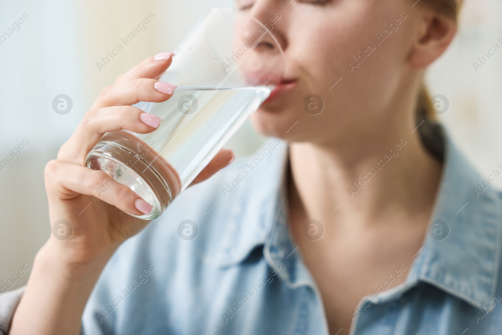 Photo of Young woman drinking water from glass at home, closeup