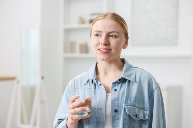 Photo of Young woman with glass of water at home