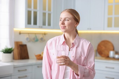 Photo of Young woman with glass of water in kitchen