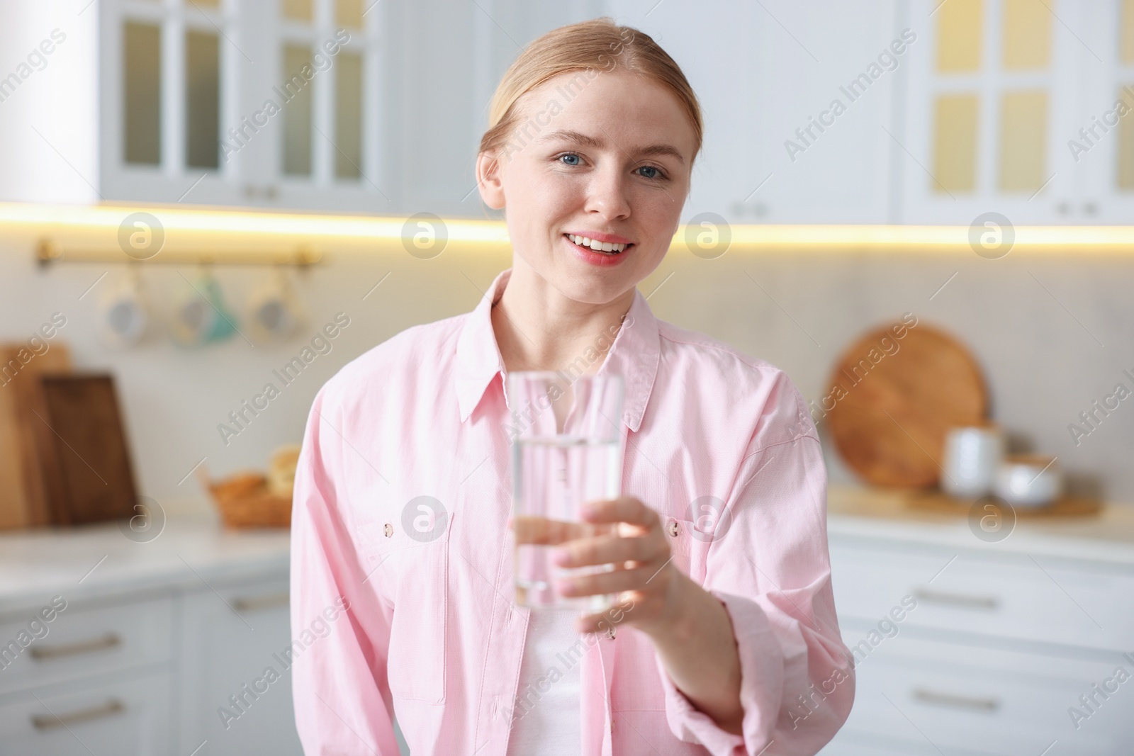 Photo of Young woman with glass of water in kitchen