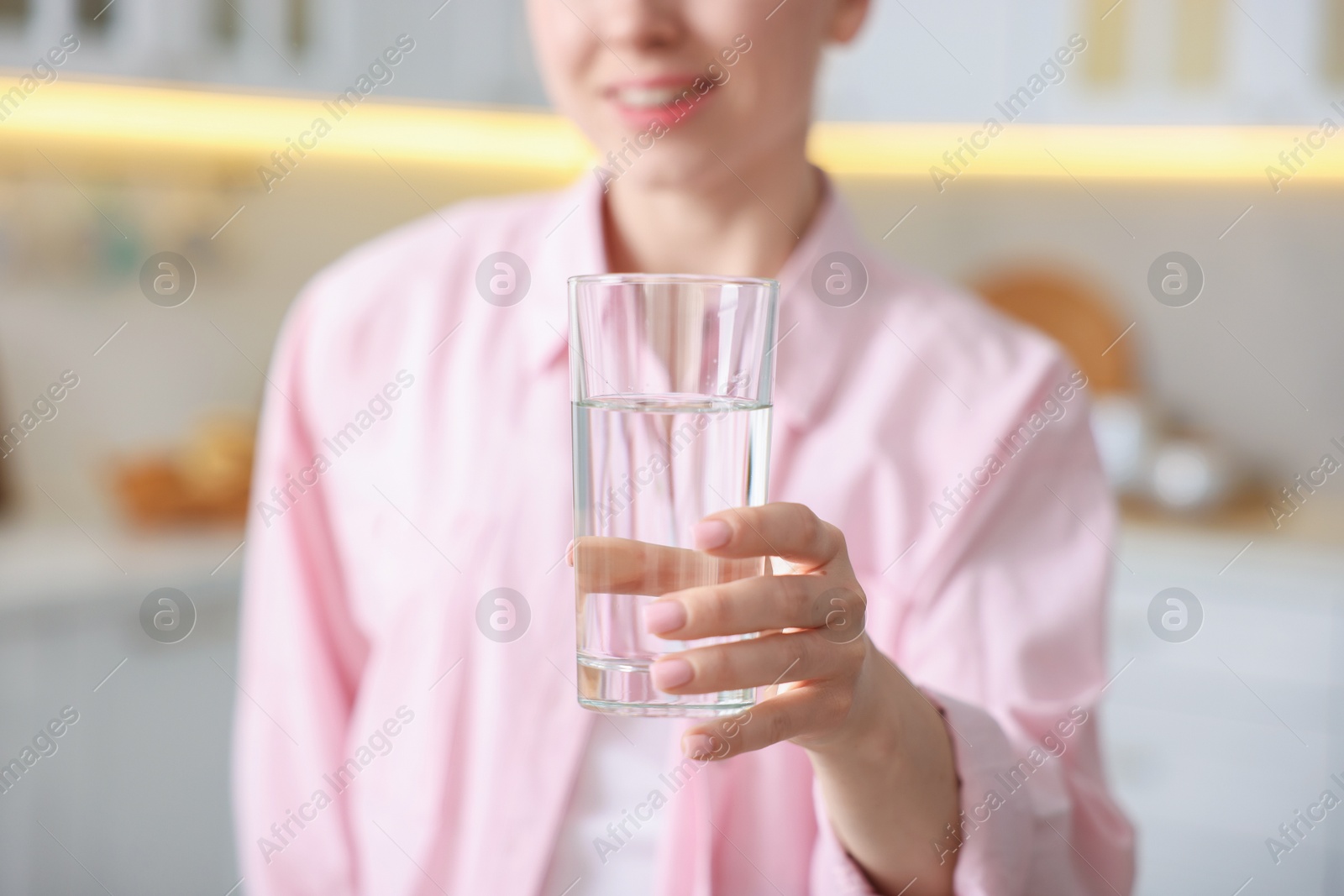 Photo of Woman with glass of water in kitchen, closeup