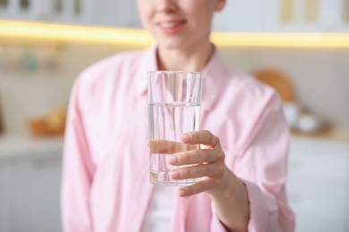 Photo of Woman with glass of water in kitchen, closeup