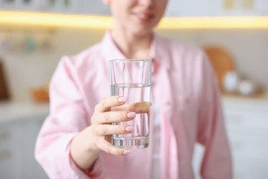 Photo of Woman with glass of water in kitchen, closeup