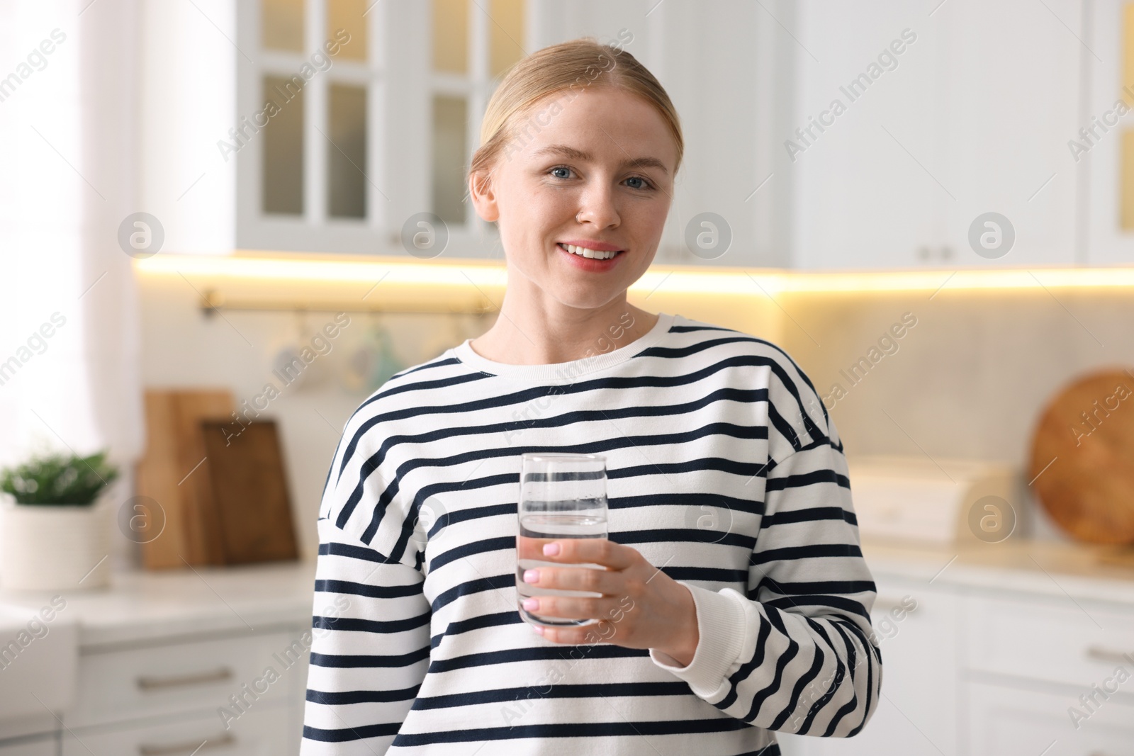 Photo of Young woman with glass of water in kitchen