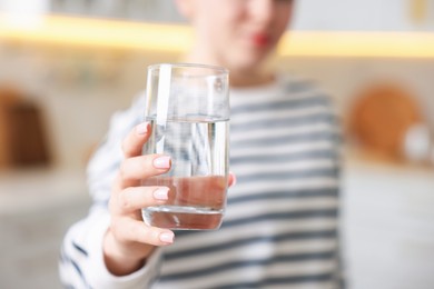 Photo of Woman with glass of water in kitchen, closeup
