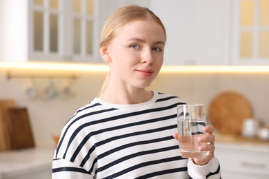 Photo of Young woman with glass of water in kitchen
