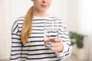 Photo of Woman with glass of water in kitchen, closeup
