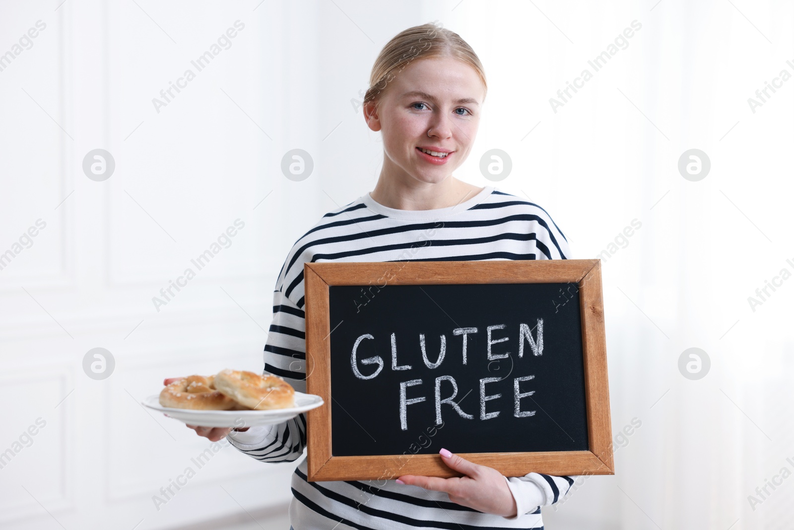 Woman holding small chalkboard with text Gluten Free and pretzels indoors Photo of Woman holding small chalkboard with text Gluten Free and pretzels indoors