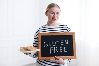 Photo of Woman holding small chalkboard with text Gluten Free and pretzels indoors
