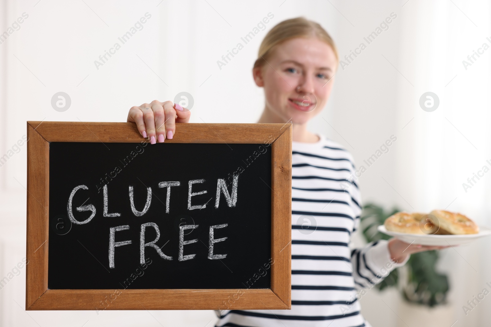 Woman holding small chalkboard with text Gluten Free and pretzels indoors, selective focus Photo of Woman holding small chalkboard with text Gluten Free and pretzels indoors, selective focus