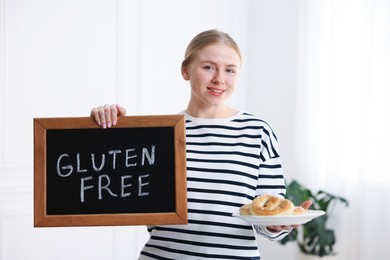 Photo of Woman holding small chalkboard with text Gluten Free and pretzels indoors
