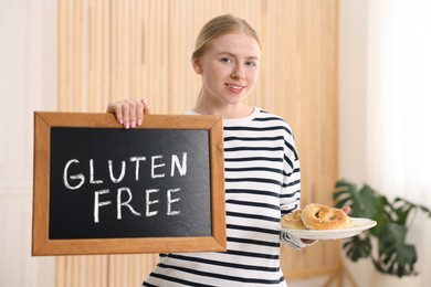 Photo of Woman holding small chalkboard with text Gluten Free and pretzels indoors