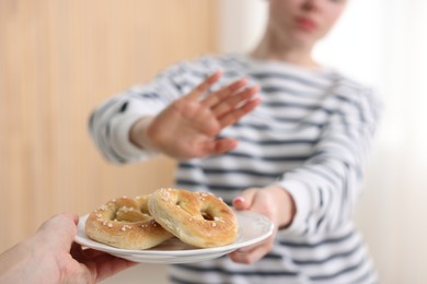 Photo of Gluten free diet. Woman refusing from pretzels indoors, selective focus