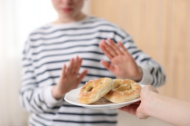 Photo of Gluten free diet. Woman refusing from pretzels indoors, selective focus