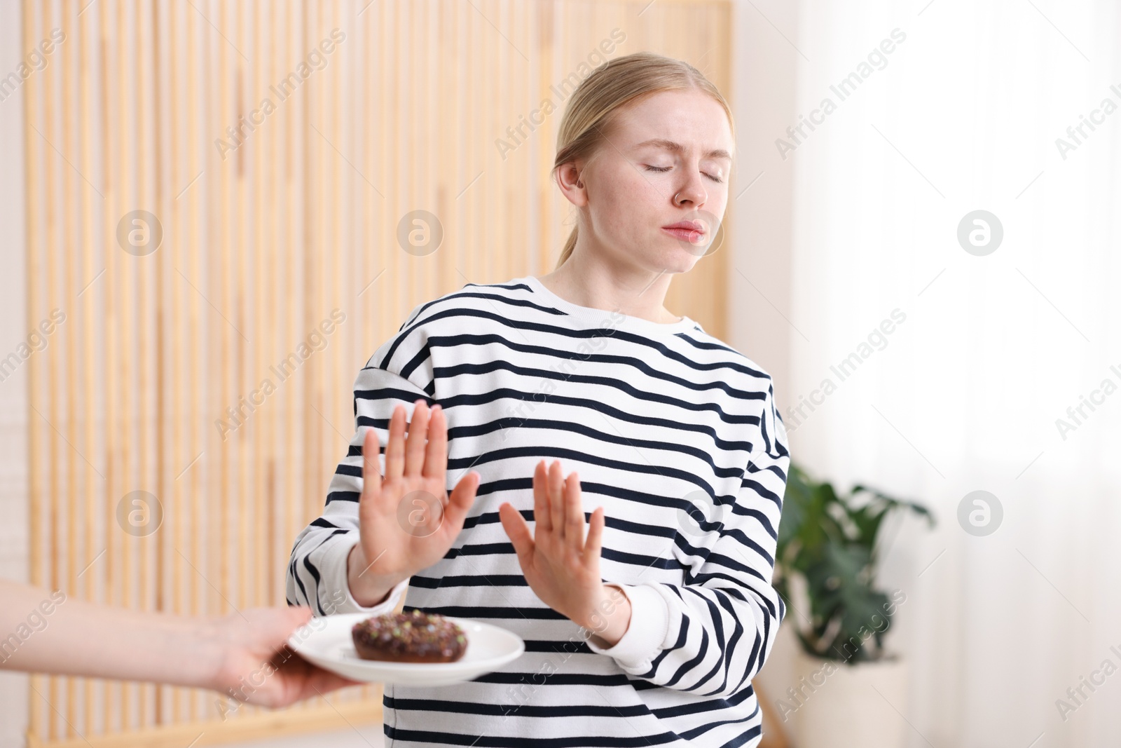 Gluten free diet. Woman refusing from donut indoors Photo of Gluten free diet. Woman refusing from donut indoors