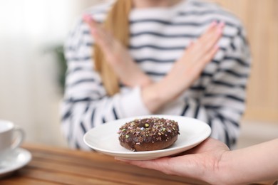 Photo of Gluten free diet. Woman refusing from donut at table indoors, selective focus