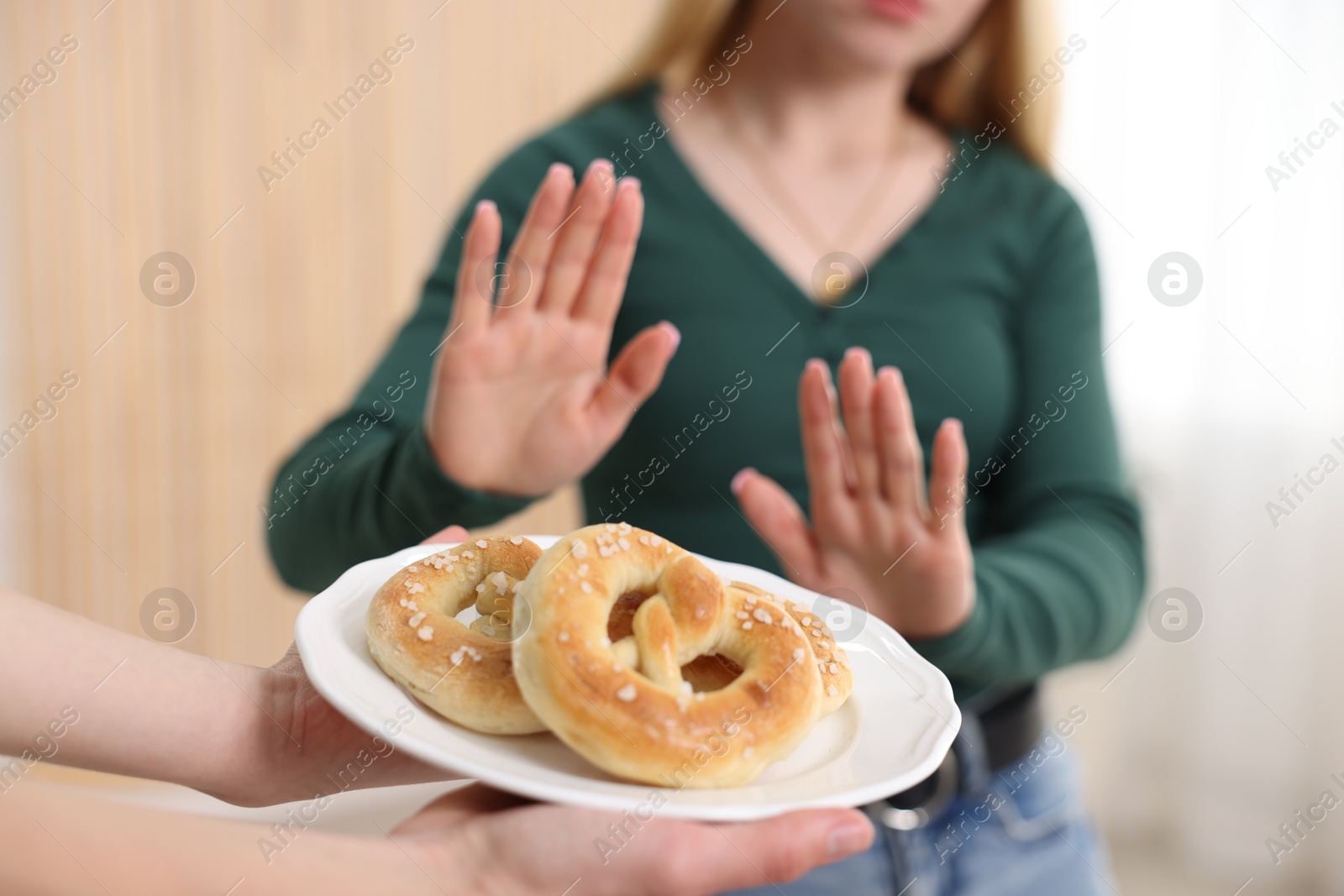Photo of Gluten free diet. Woman refusing from pretzels indoors, selective focus