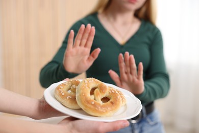Photo of Gluten free diet. Woman refusing from pretzels indoors, selective focus