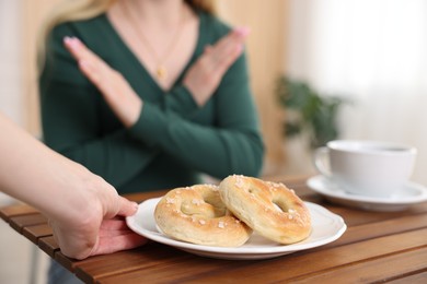 Photo of Gluten free diet. Woman refusing from pretzels indoors, selective focus