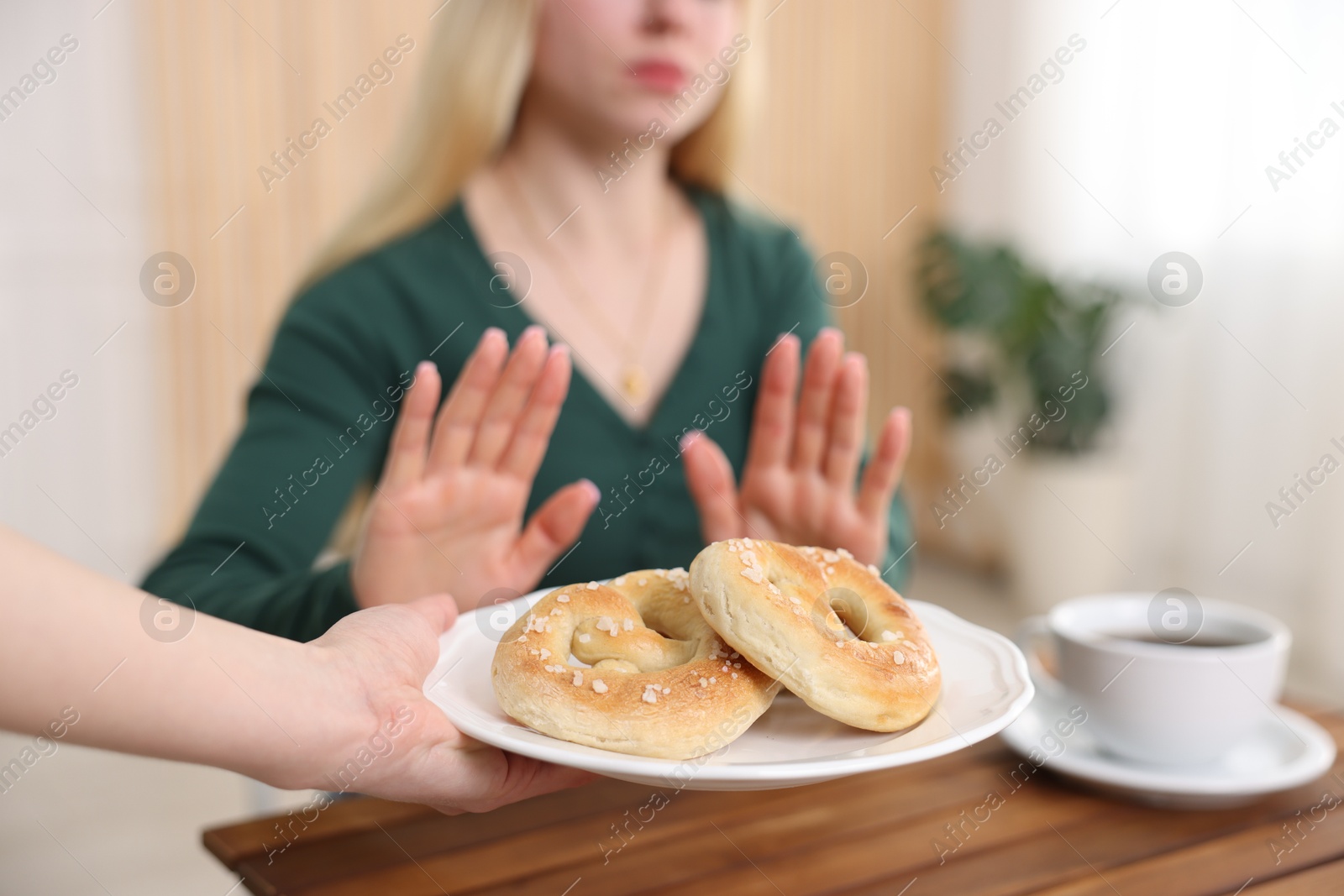 Gluten free diet. Woman refusing from pretzels indoors, selective focus Photo of Gluten free diet. Woman refusing from pretzels indoors, selective focus
