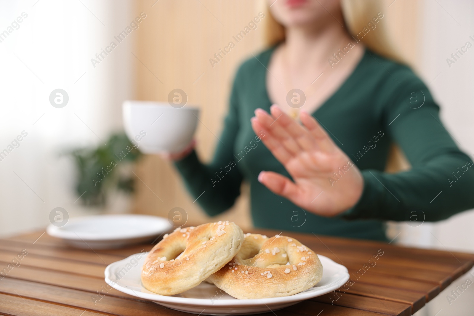 Photo of Gluten free diet. Woman refusing from pretzels indoors, selective focus