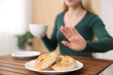 Photo of Gluten free diet. Woman refusing from pretzels indoors, selective focus