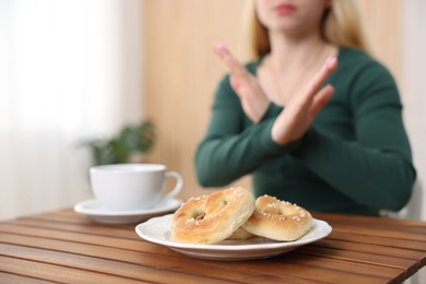 Photo of Gluten free diet. Woman refusing from pretzels indoors, selective focus