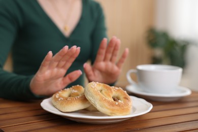 Photo of Gluten free diet. Woman refusing from pretzels indoors, selective focus