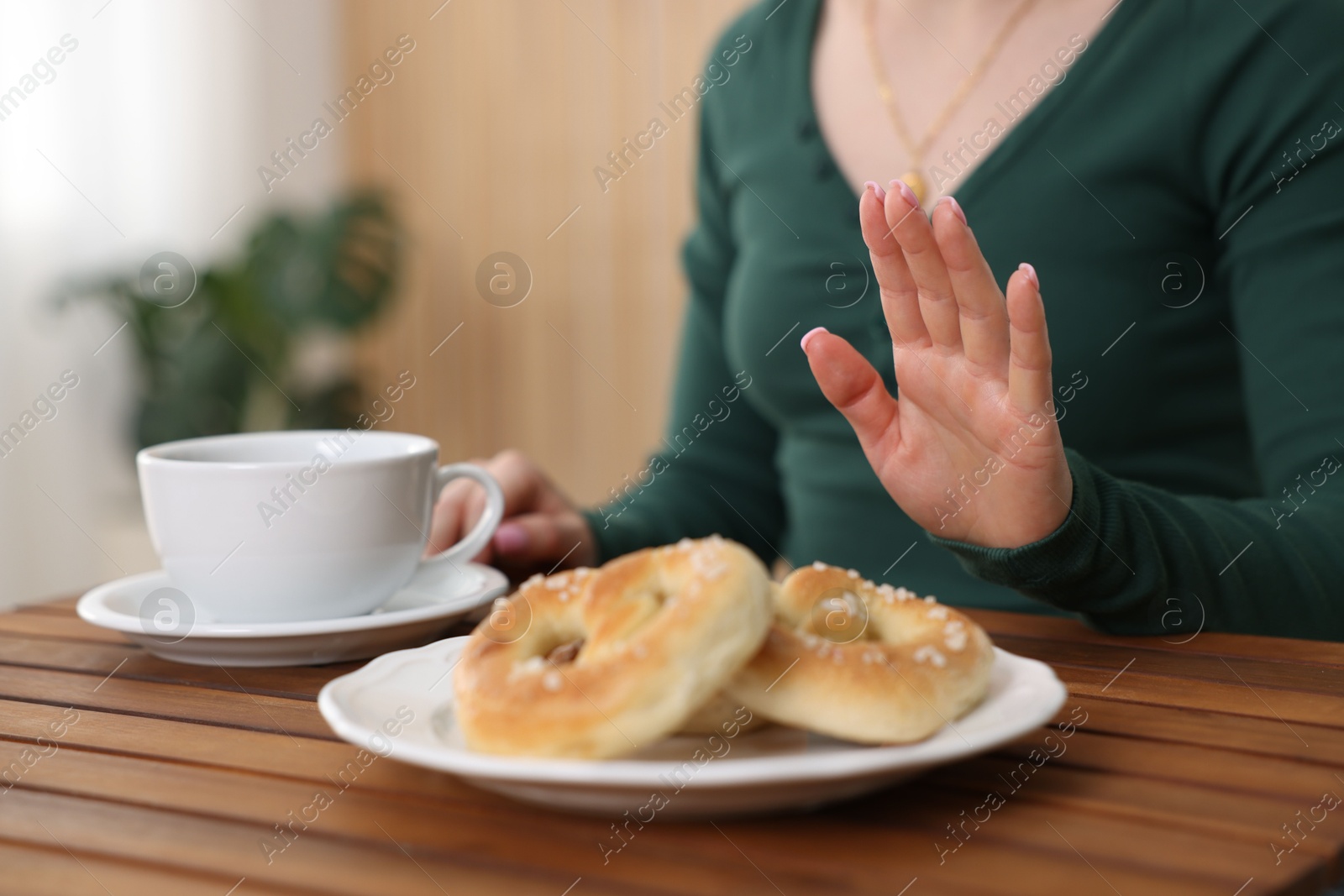 Gluten free diet. Woman refusing from pretzels indoors, closeup Photo of Gluten free diet. Woman refusing from pretzels indoors, closeup