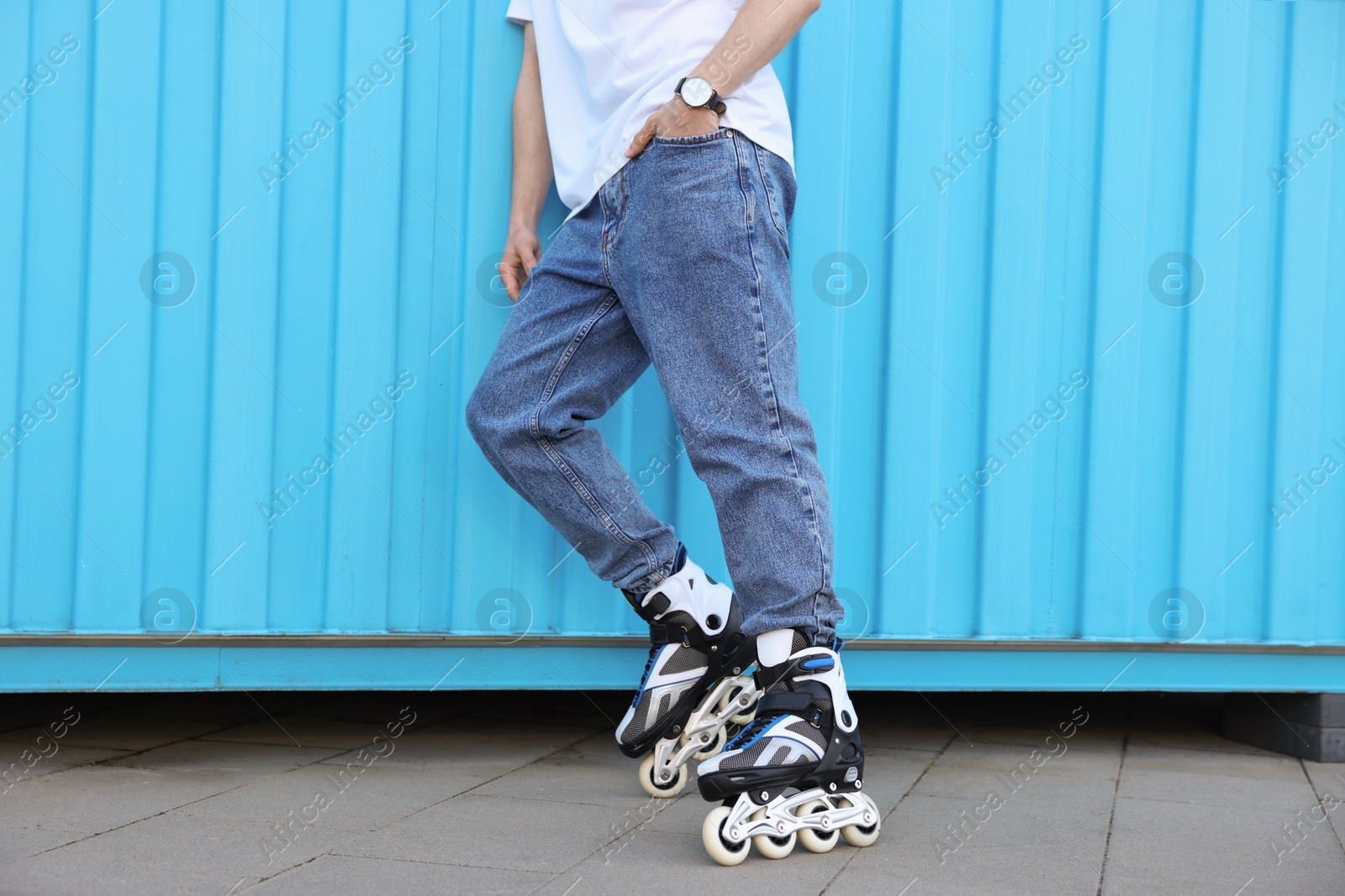 Man with roller skates near light blue wall outdoors, closeup Photo of Man with roller skates near light blue wall outdoors, closeup