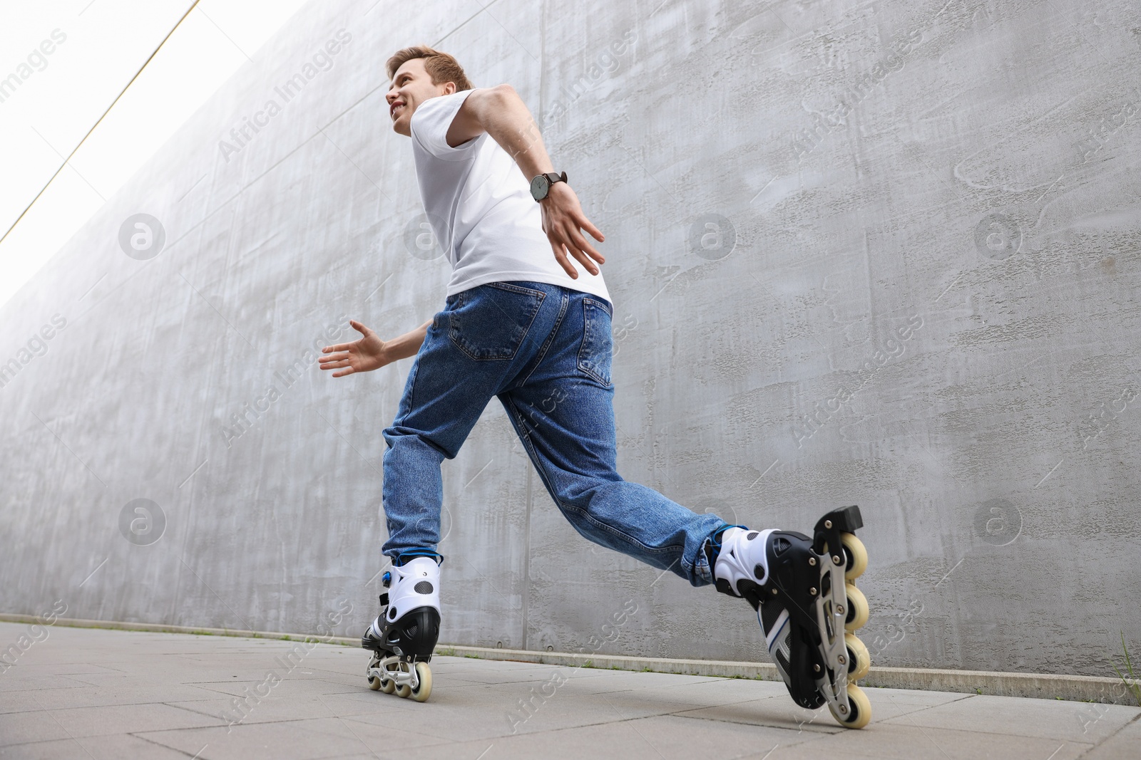 Photo of Happy young man roller skating on street, low angle view