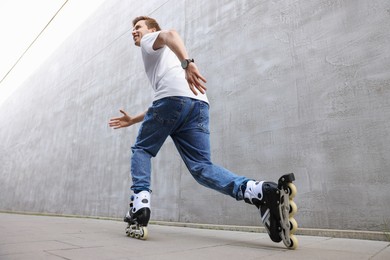 Photo of Happy young man roller skating on street, low angle view