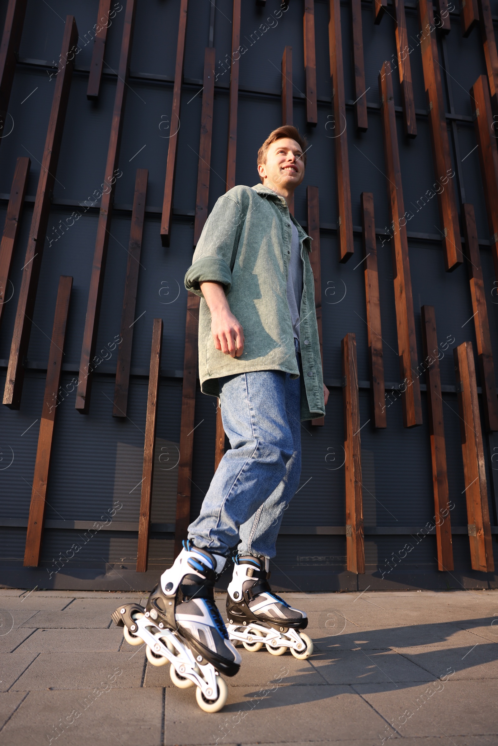 Photo of Young man with roller skates outdoors, low angle view