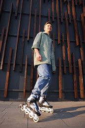 Photo of Young man with roller skates outdoors, low angle view