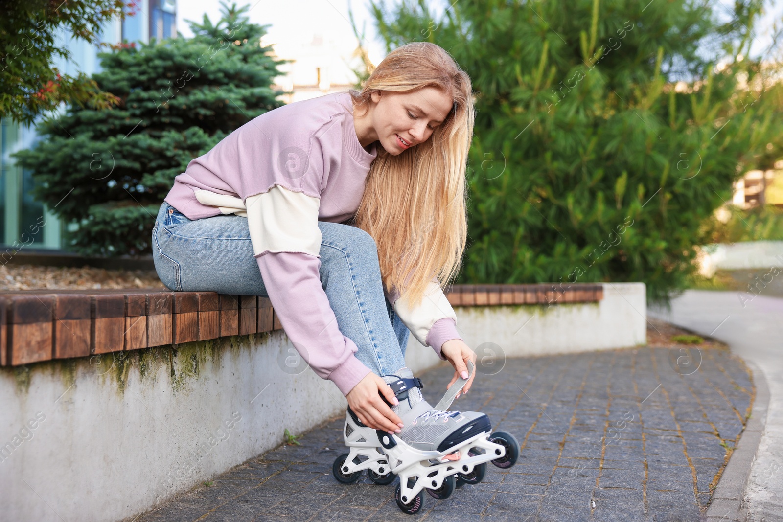 Beautiful woman putting on roller skates outdoors Photo of Beautiful woman putting on roller skates outdoors