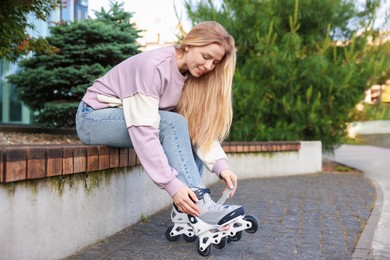 Photo of Beautiful woman putting on roller skates outdoors