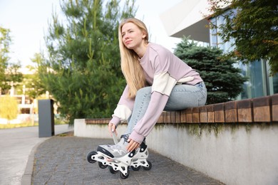 Photo of Beautiful woman putting on roller skates outdoors