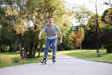 Photo of Young man roller skating in park on summer day