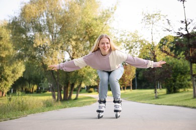 Photo of Happy young woman roller skating in park