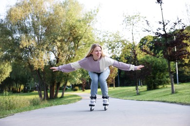 Photo of Happy young woman roller skating in park