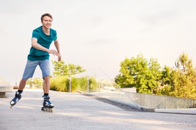 Photo of Happy man roller skating on city street. Space for text