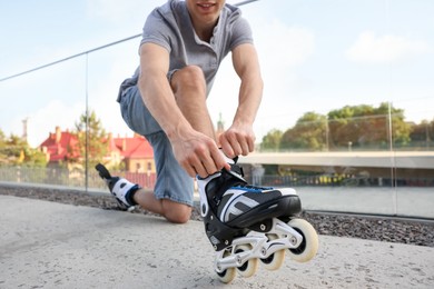 Photo of Man putting on roller skates outdoors, closeup