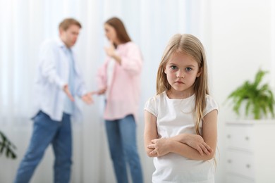 Photo of Upset little girl and her parents fighting at home, selective focus