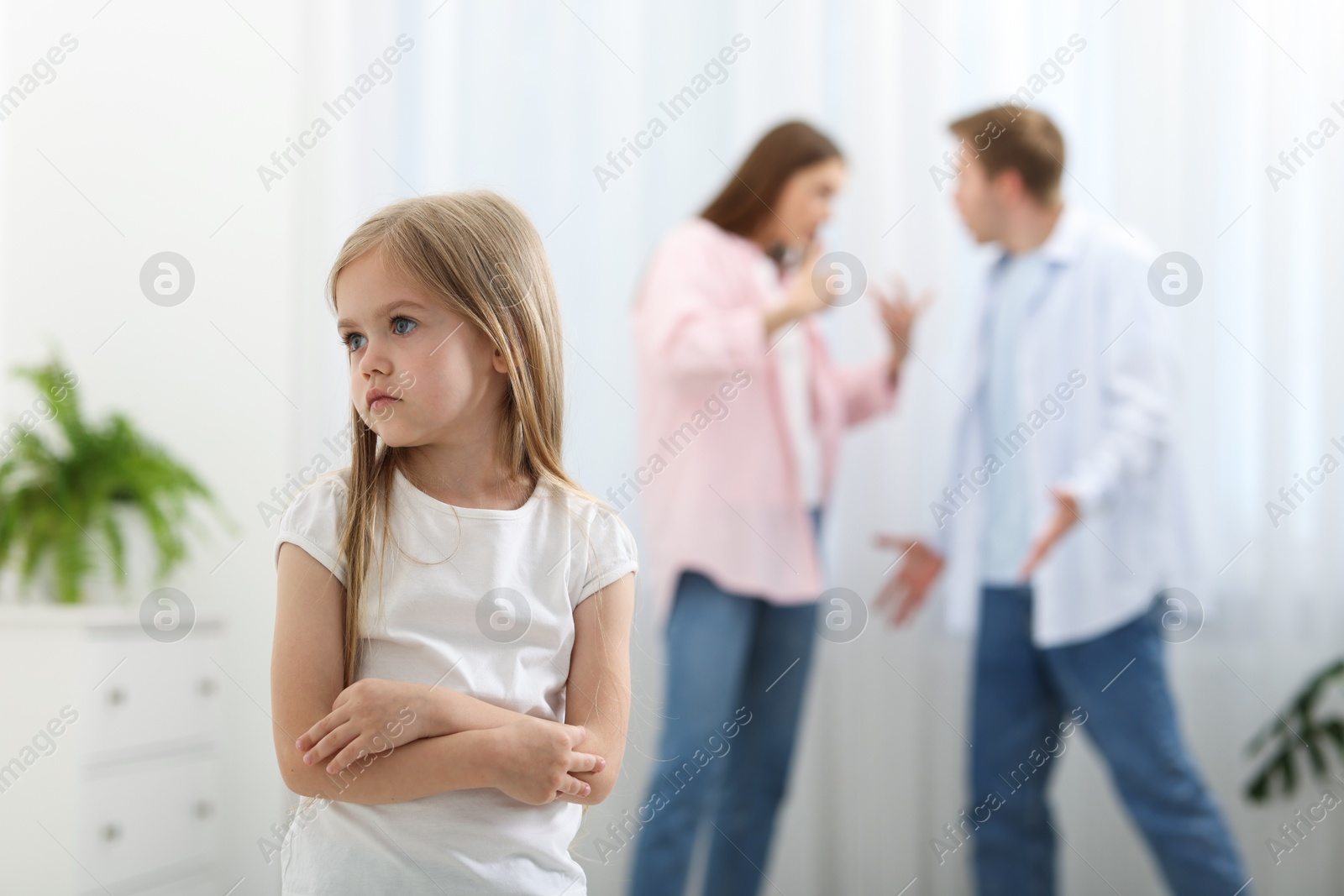 Photo of Upset little girl and her parents fighting at home, selective focus